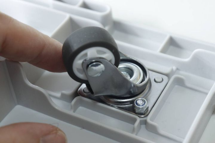 白いキャリー台車のキャスター部分を指で回しているアップ