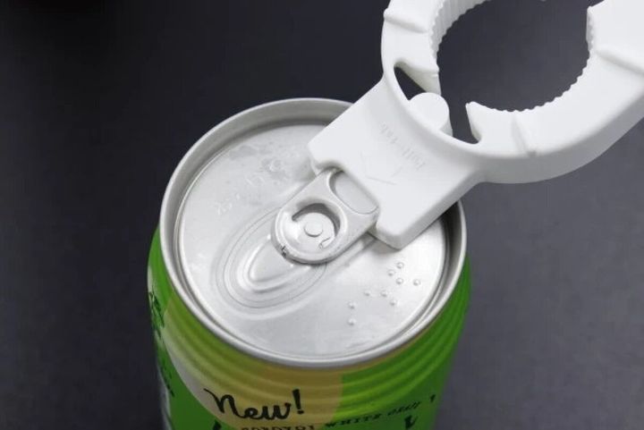 白い多機能オープナーで緑色の缶のプルトップを開けようとしている様子