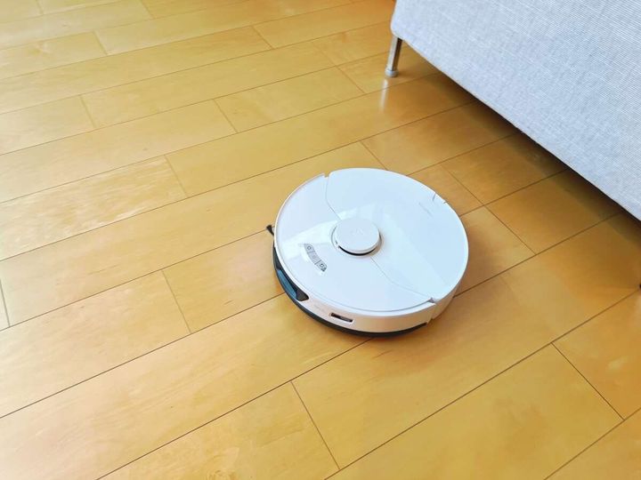 木のフローリングを掃除する白いロボット掃除機