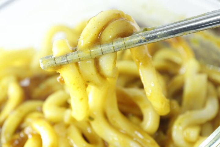 箸でカレーうどんの麺をすくい上げ、とろみのあるスープが絡んでいる
