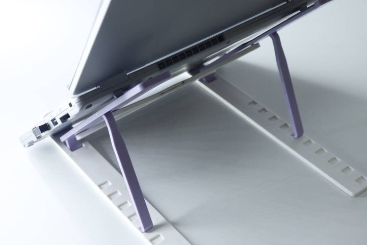 パープルとホワイトのPC・タブレットスタンドにノートPCを乗せて使用している様子