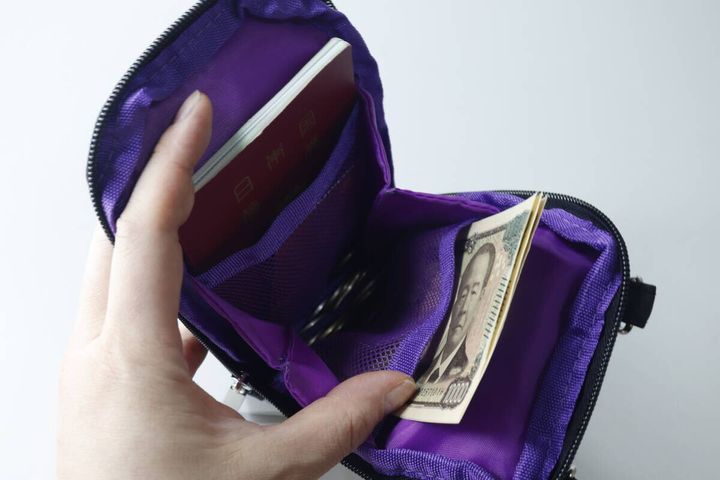 紫色のポーチのポケットにパスポートと千円札が収納されている