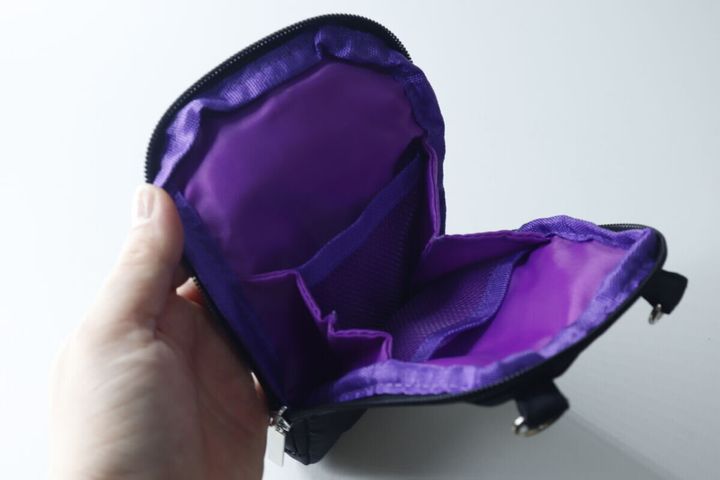 内側が鮮やかな紫色のポーチを開き、複数の仕切りが見える