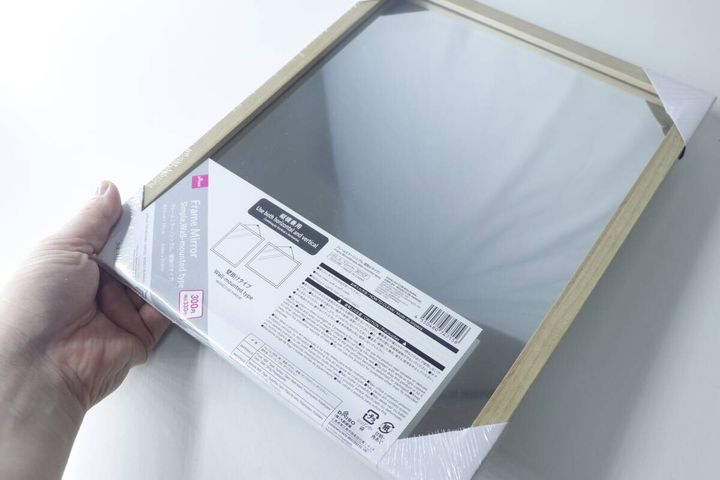 手で持ったダイソーの壁掛けミラーのパッケージ