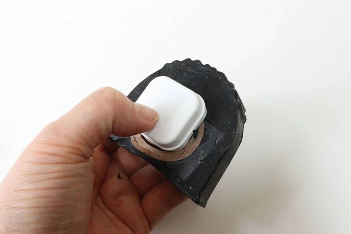 手が白い石けんホルダーを黒い石けんに埋め込んでいる
