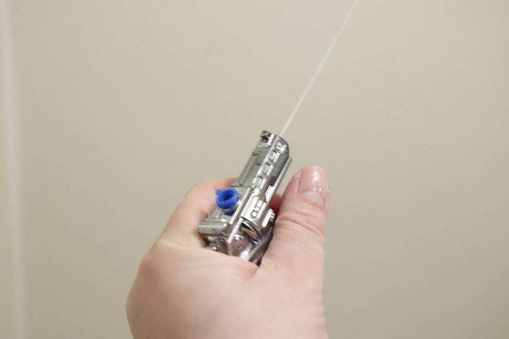手に持った水鉄砲キーホルダーから勢いよく水が一直線に発射される