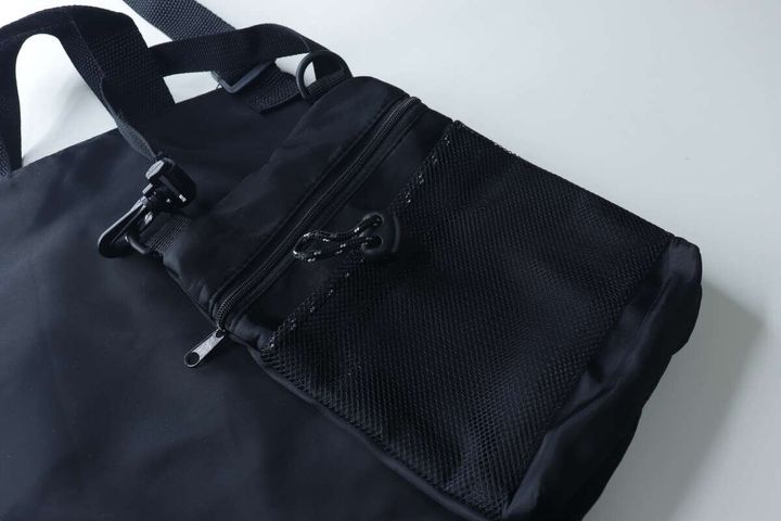 黒い縦型ショルダーバッグを別の大きな黒いバッグに装着している様子