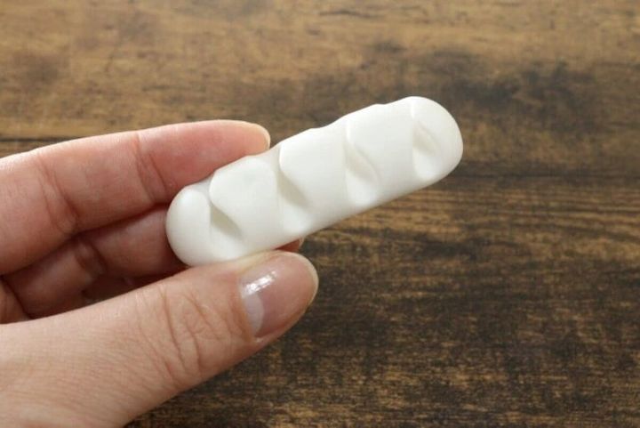 白いケーブルホルダーを女性の手が持っている様子
