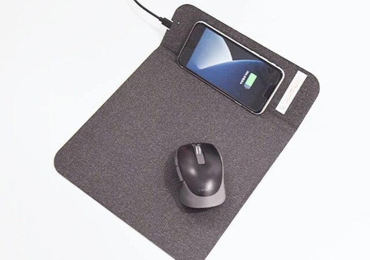 グレーのマウスパッドにスマホとマウスが置かれ、スマホは充電中