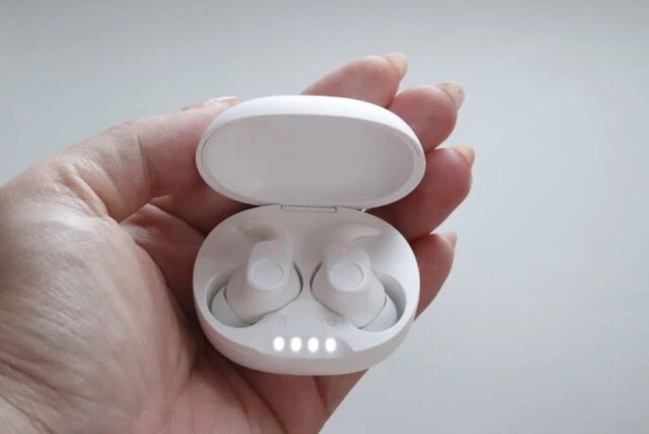 白いワイヤレスイヤホンが充電ケースに入り、女性の手のひらに乗っている
