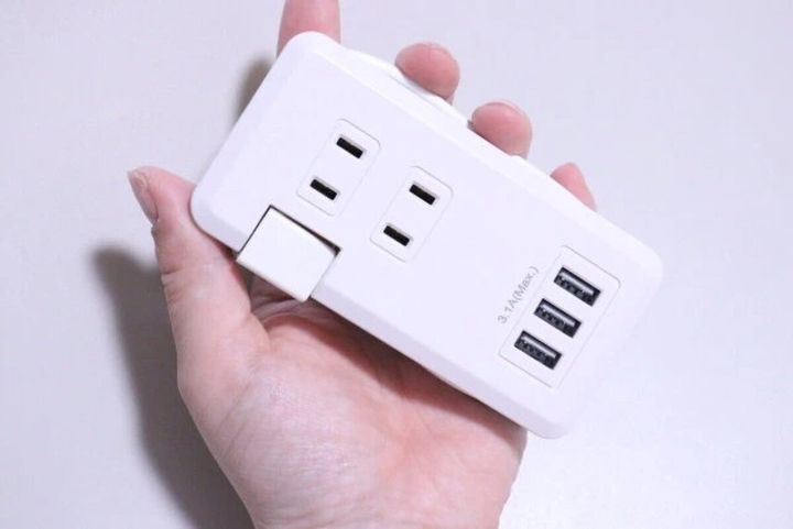 白い2口コンセントタップと3つのUSBポートを女性の手のひらに乗せている