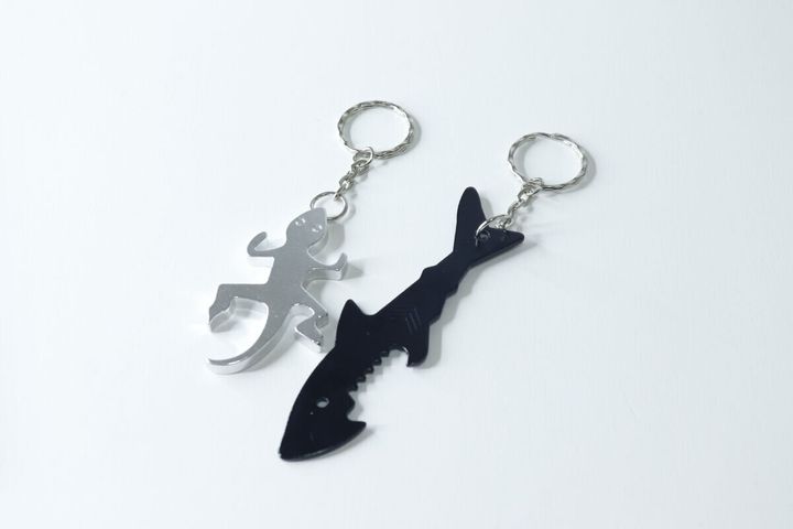 銀色のトカゲ型と黒いサメ型の栓抜きキーホルダーが並べられている