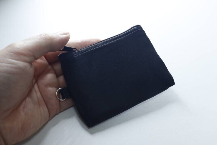 女性の手のひらに乗せられた黒いミニソフトクッションポーチ