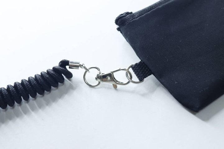 ポーチのDカンにカラビナ付きのコイルストラップが取り付けられている