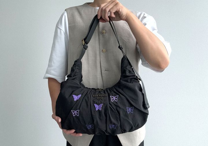 黒いクロワッサンバッグを手に持った女性の全身