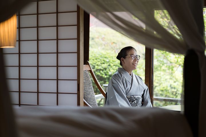 「泉亭」の天蓋付きベッドの向こうで。窓外では庭の緑が映え、紅葉の季節は格段に美しいという。