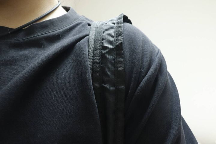 黒いTシャツの人がバッグを肩にかけショルダーベルトが写る