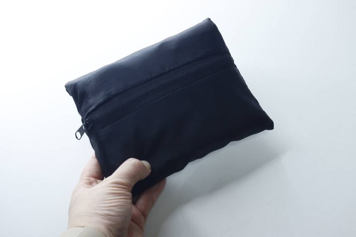 手でコンパクトにたたまれた黒いバッグを持っている
