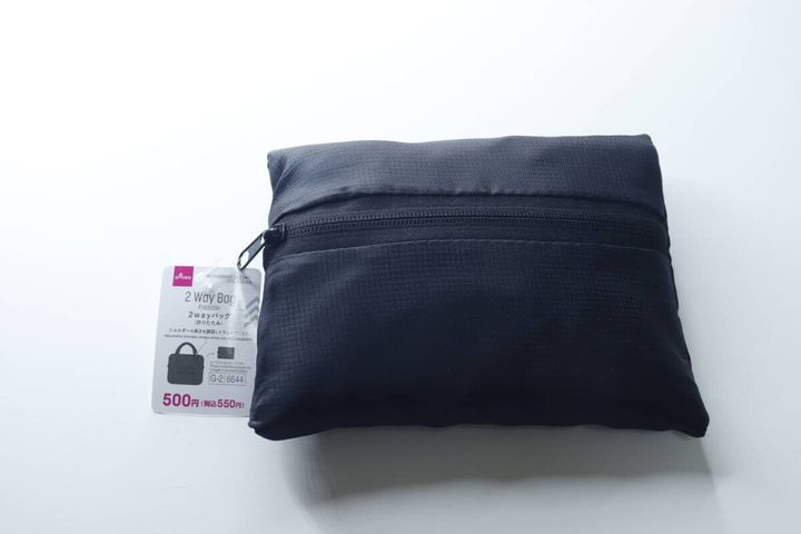 黒い折りたたみバッグがたたまれ商品タグが付いている