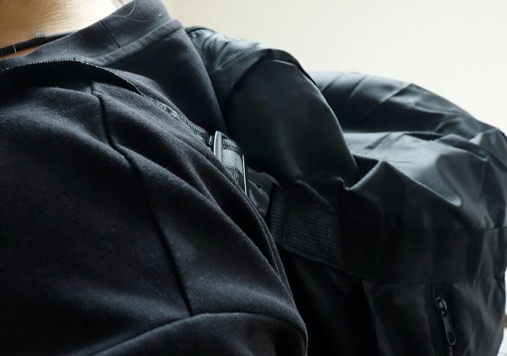 黒いTシャツの人がバッグをリュックとして背負っている