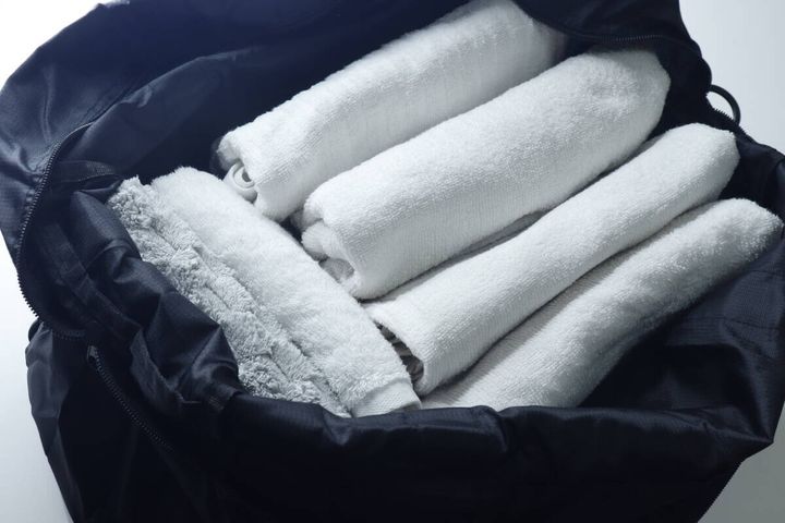 広げた黒いバッグに白いバスタオルとハンドタオルが入っている