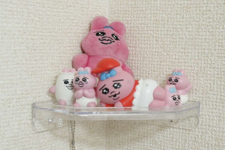 クリアコーナーラックにピンク色のマスコットやぬいぐるみが飾られている