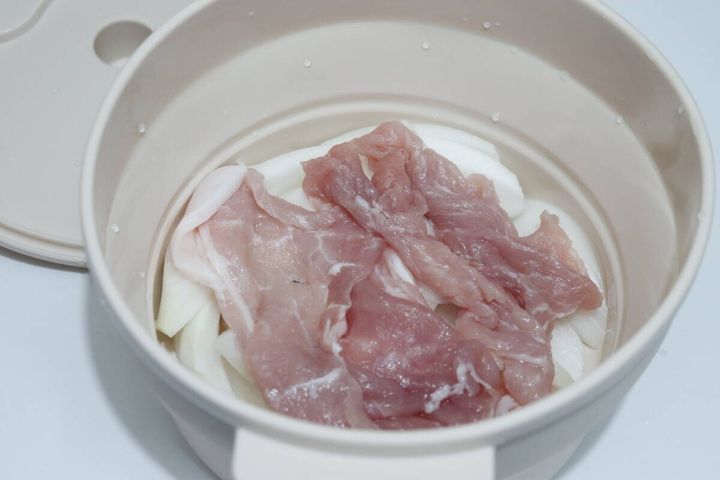 シリコンスチーマーにスライス玉ねぎと豚肉を入れている