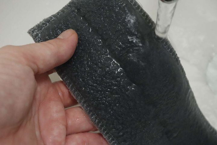 手が「首振り網戸クリーナー」のマイクロファイバー部分に水をたっぷり含ませている様子