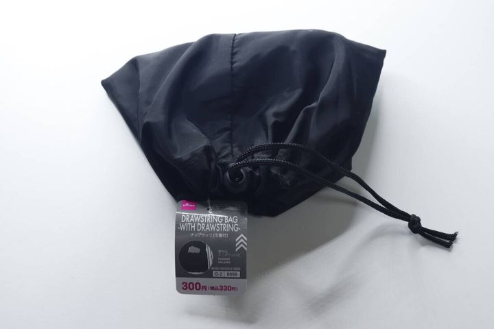 黒い巾着型にたたまれたナップサックと商品タグ