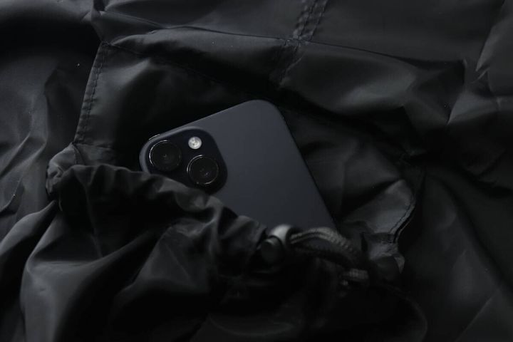 ナップサックのポケット部分に黒いスマートフォンが入っている