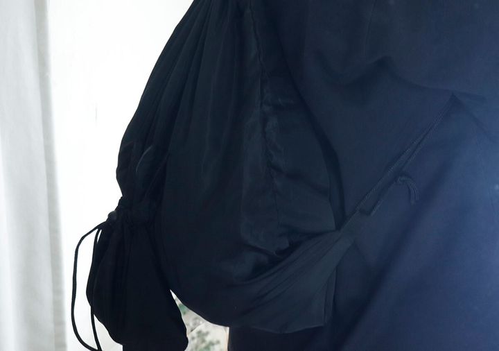 黒いナップサックを背負っている人の上半身と腕