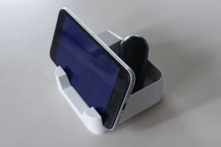 白い卓上収納ケースに横向きのスマートフォンと黒いペンが収納されている