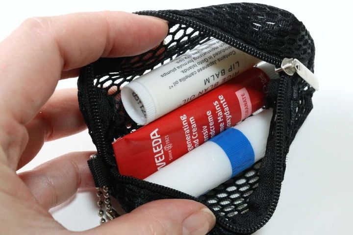 黒いメッシュポーチの中にリップクリームやハンドクリームを入れている手元