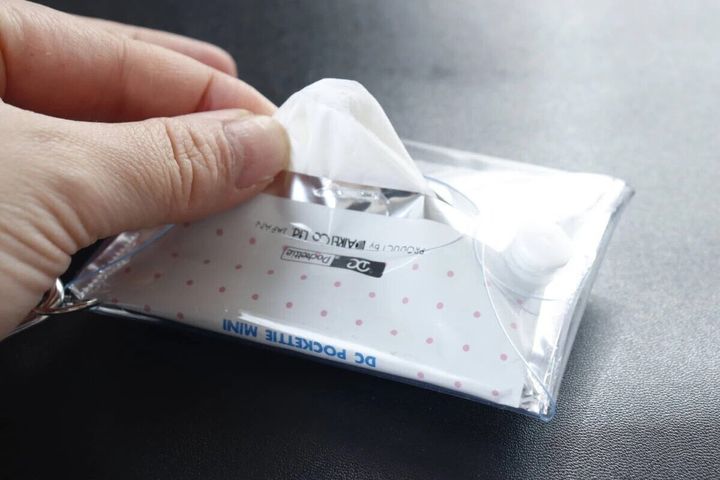 カラビナ付きティッシュポーチの裏側から白いティッシュを引き出している手元