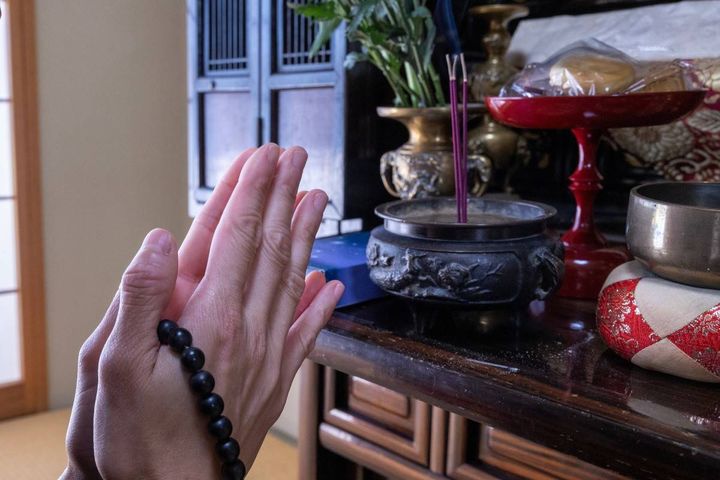 仏壇の前で手を合わせる人