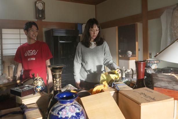 多額の借金を抱えた大学の研究員・清恵。それぞれの自宅や実家が生活感たっぷりに写される [c]2026「マジカル・シークレット・ツアー」製作委員会