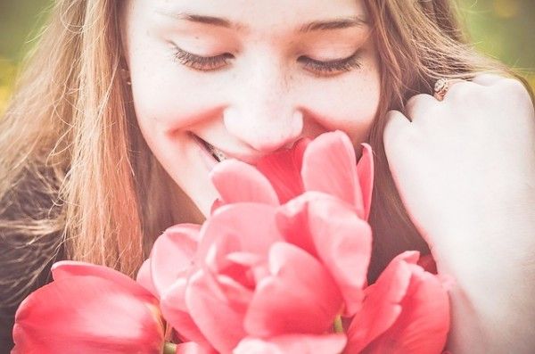 花の香りを嗅ぐ女性
