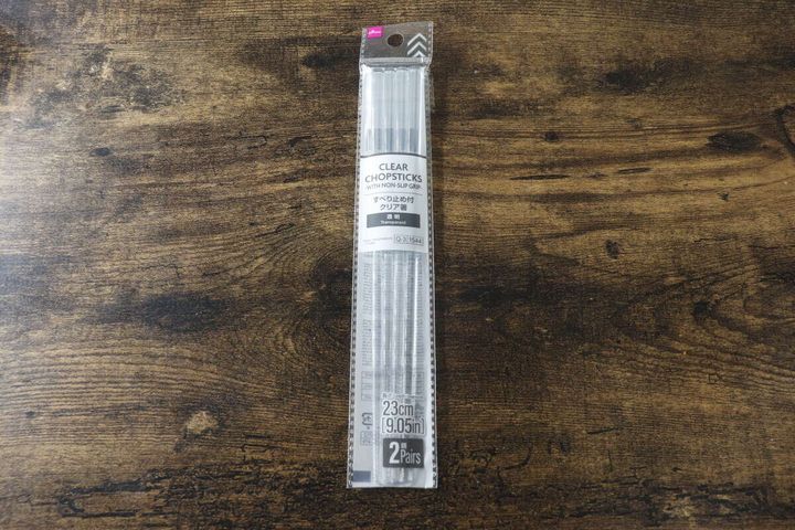 木目のテーブルに置かれたダイソーのクリア箸のパッケージ