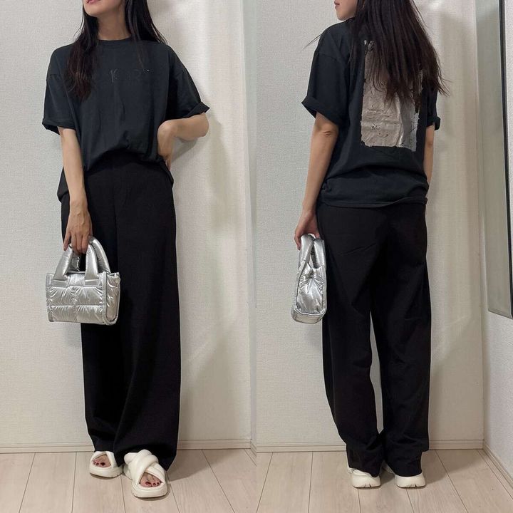 黒Tシャツと黒パンツのカジュアルコーデ。女性がシルバーのバッグを持つ
