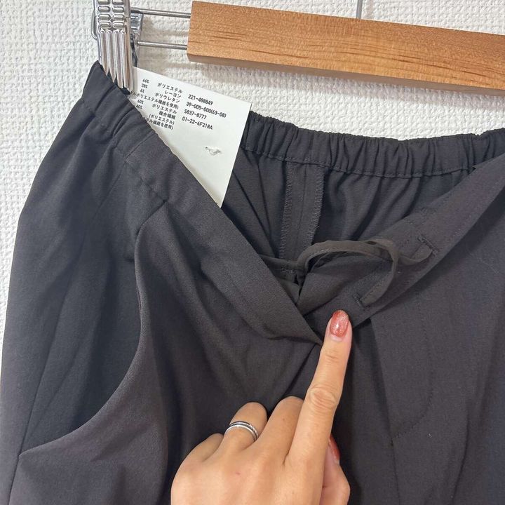 女性の指がパンツのウエスト内側の紐を指しているクローズアップ