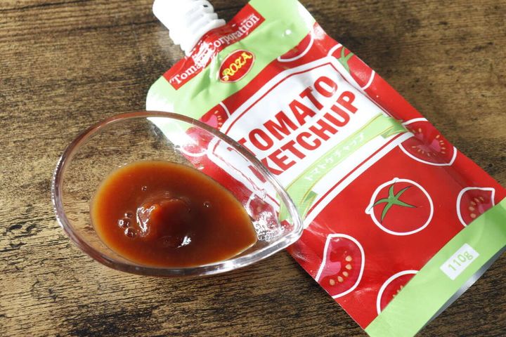 小皿に盛られた茶色いトマトケチャップと、その横に置かれたパウチケチャップ