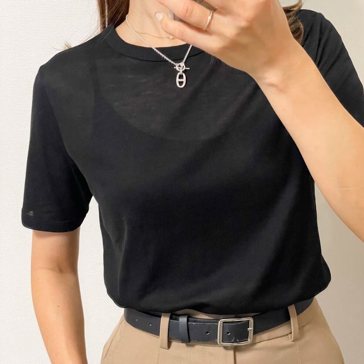 黒いシアーTシャツを着た女性の胸元アップ。ネックレスとベルトが見える。