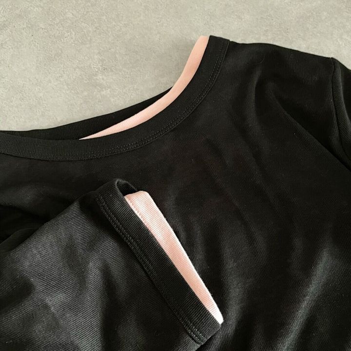 黒いTシャツの襟元と袖口のアップ。袖からピンクの生地が見える。