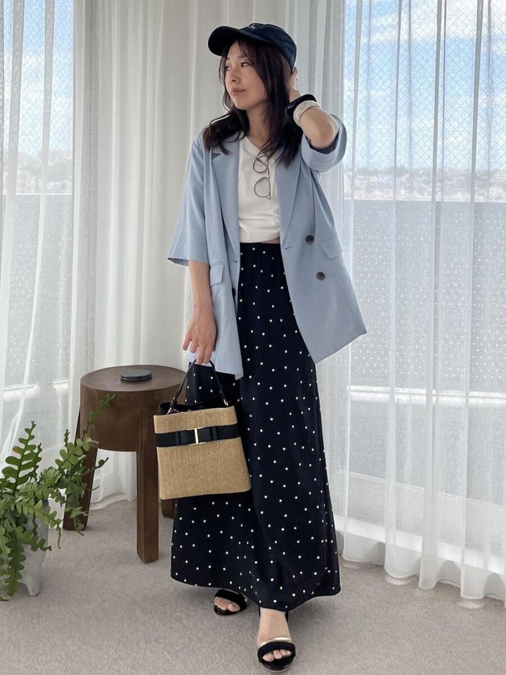 黒ドット柄スカートに水色ジャケットとキャップを被った女性