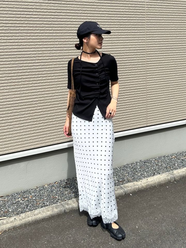 白ドット柄スカートに黒トップスとキャップを被った女性