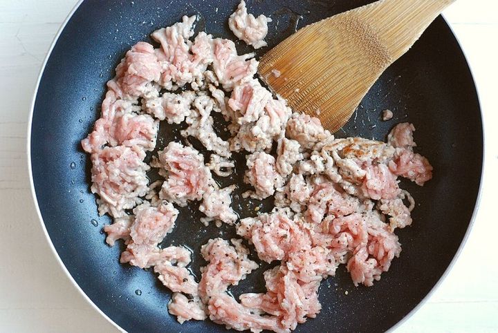 フライパンで豚ひき肉を木べらで炒めている様子
