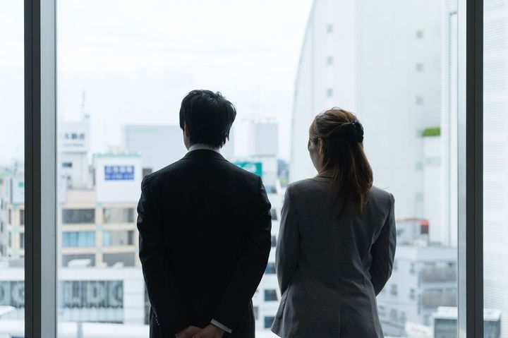 並んでオフィスの窓から外を見ている男女