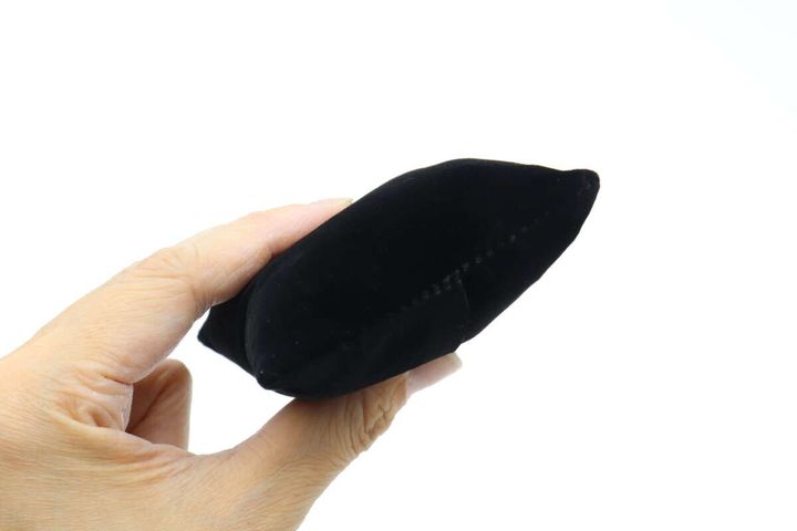 黒いベロア素材の腕時計用クッションを手に持つ