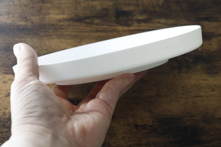 白い回転式物置トレーを片手で持ち上げている様子。横から見た厚みがわかる