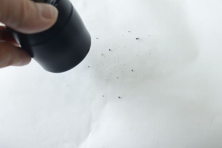 ペッパーミルで白い紙の上に山椒を挽いている手元